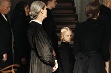 In die Sonne schauen Ein blondes Mädchen steht zwischen weiteren Personen und blicktin die Kamera.