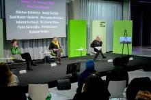 Von links nach rechts Sasha Marinna Salzmann, Sabine Hark, Ines Kappert und Peggy Piesche vor der Leinwand auf dem Podium, die Namen der Opfer des Anschlags in Hanau 2020 auf der Leinwand