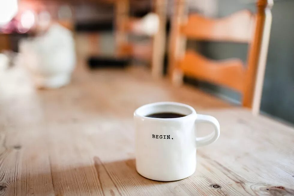 the word "begin" written on a mug which stands on a table