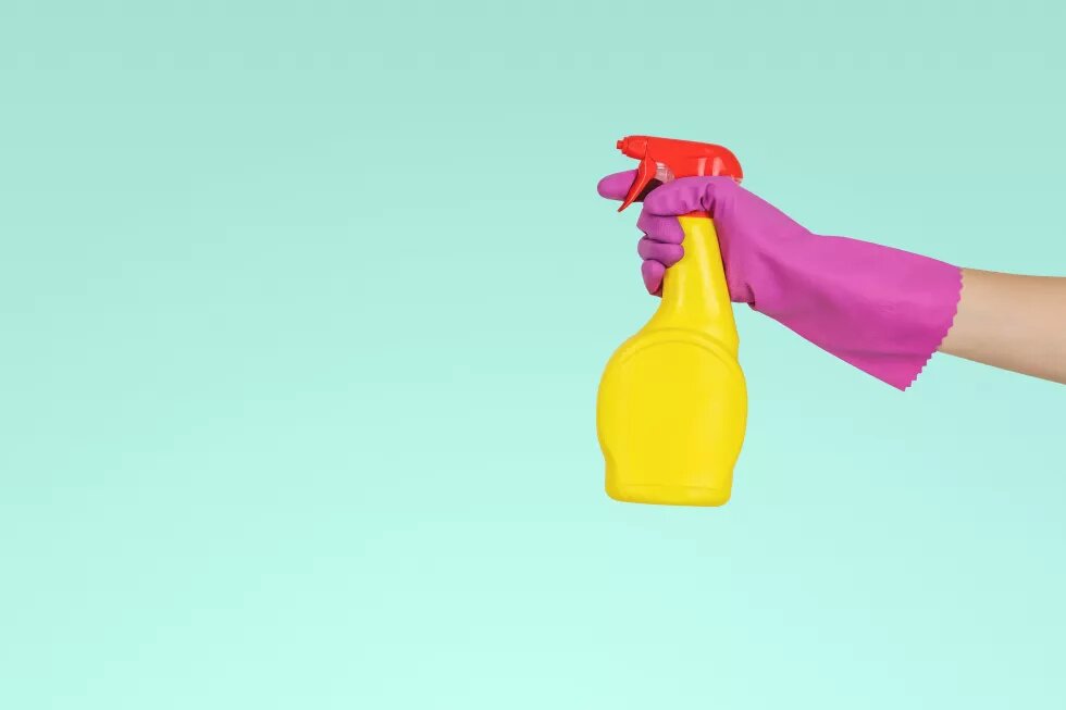 hand in gloves holds spray bottle