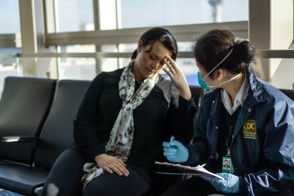 A public health officer is asking questions to a sick traveller at an airport.