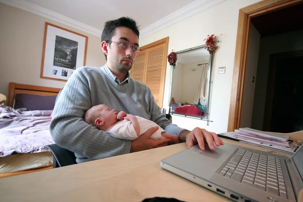 dad at home working on computer and holding baby