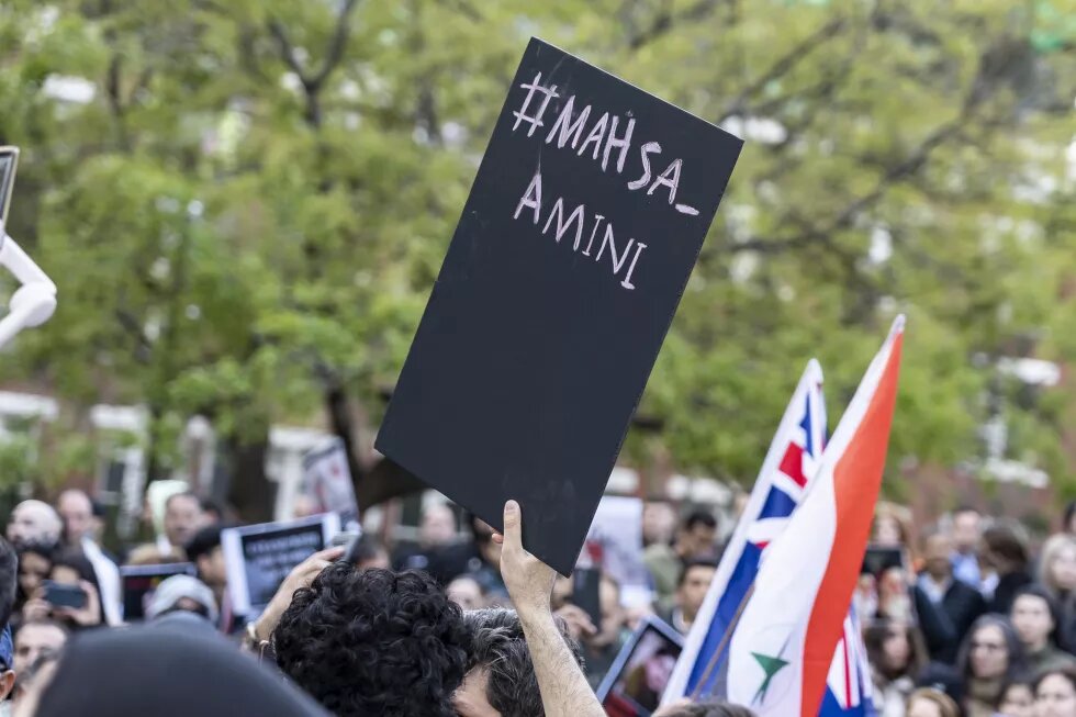 Protests with black sign and caption "#Mahsa Amini"