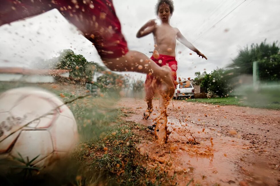 Kinder spielen Schlammfußball auf der Straße