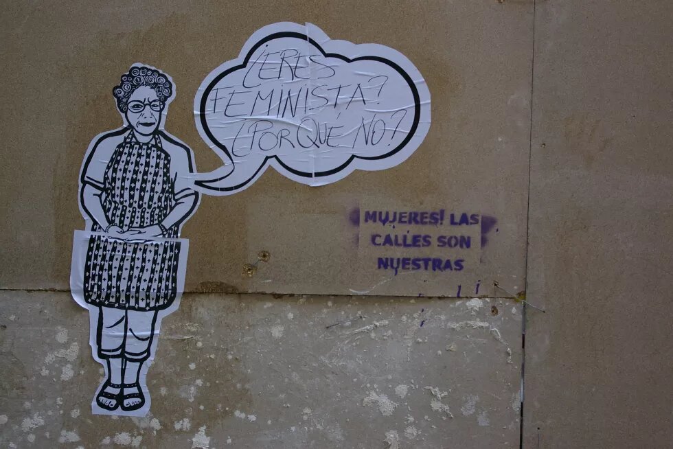 Foto von Streetart. Eine aufgeklebte Frau aus Papier fragt in einer Sprechblase, ob der*die Leser*in Feminist*in sei. 