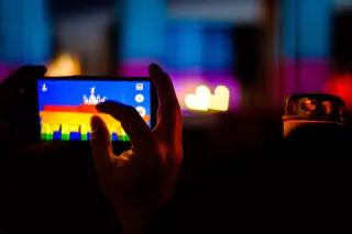 Das in regenbogenfarben erleuchtete Brandenburger Tor in einem Handy-Display.